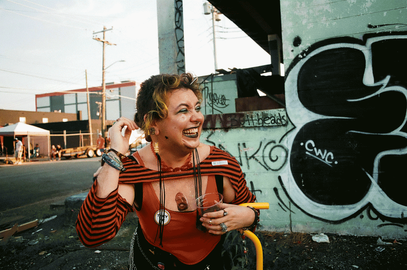 Person standing in front of a graffitied wall, leaning forward and laughing