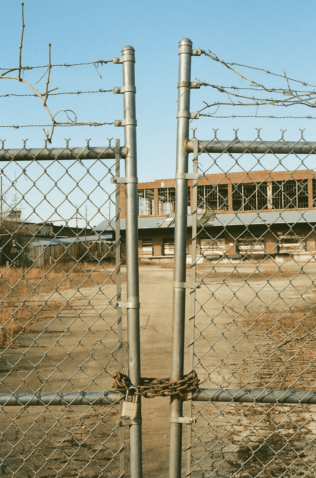 Locked fence with decaying building behind it