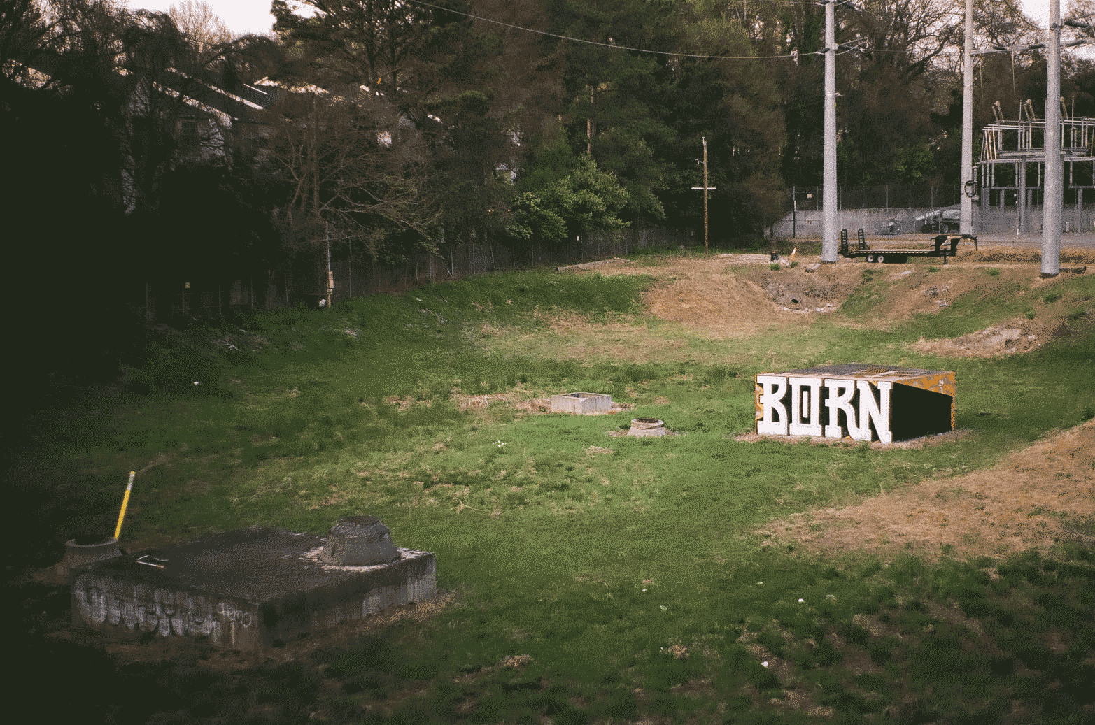 Empty field with a concrete block in the middle - graffiti saying 'born' sprayed across it