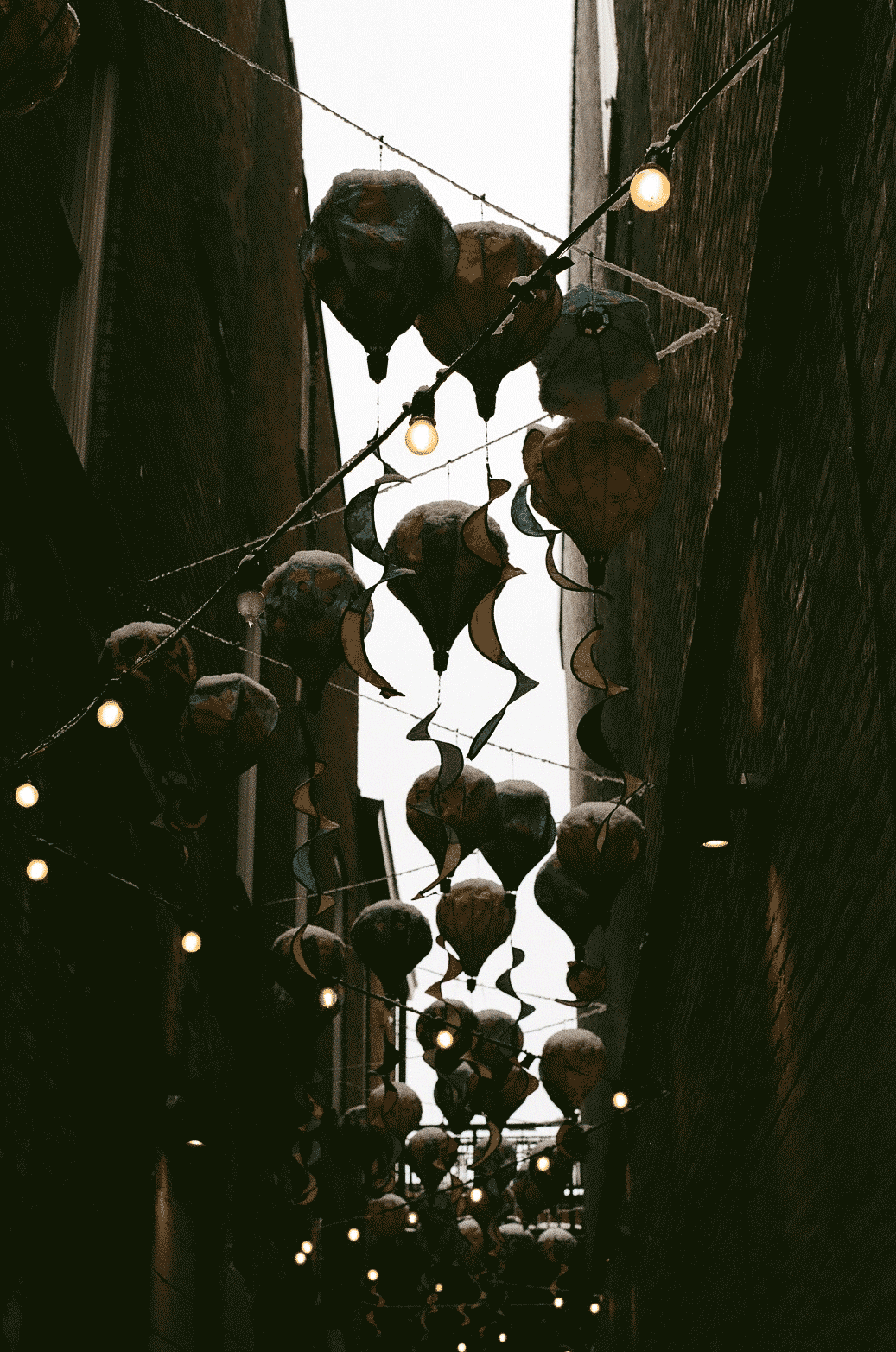 View from below of small air balloons hanging in an alleyway with snow on them